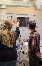 A team of people stand around a hospital bed