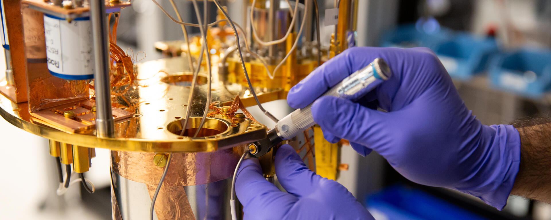 Gloved hands working on quantum lab equipment