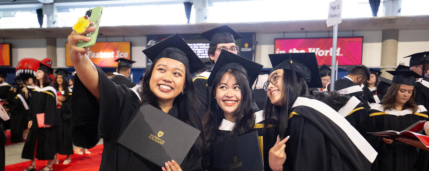 Three graduates take a selfie together