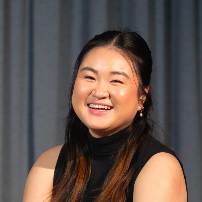 A woman sits infront of a stage curtain