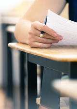person sitting at a desk writing an exam