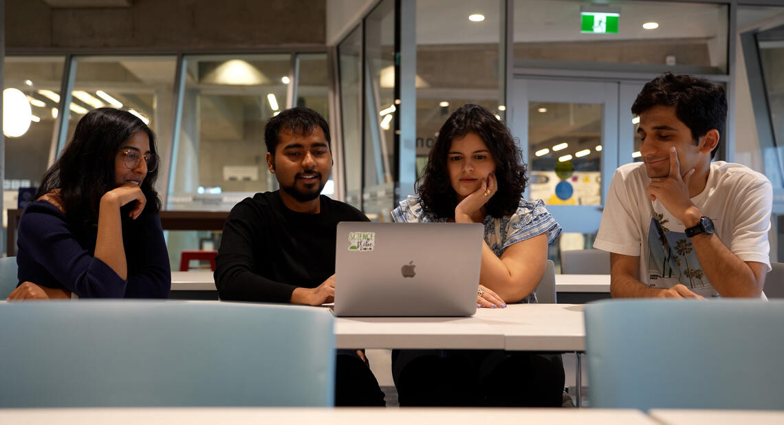 A group of students look at a laptop