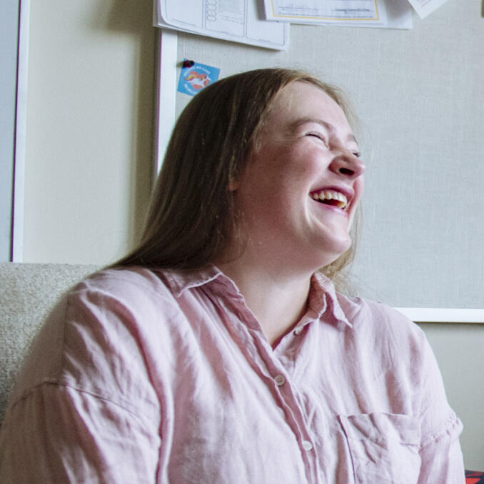 A woman smiles in a pink shirt