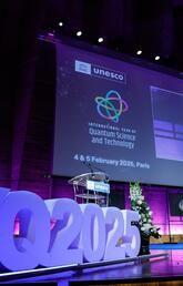 A stage bathed in blue light while speakers on a panel have a discussion