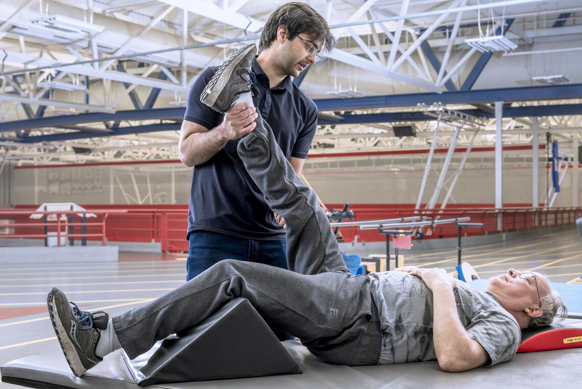 A man performs a stretch on a rehab patient