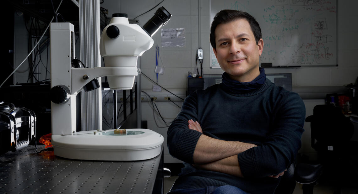 A man sits next to a microscope