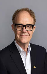 A man with glasses and a black suit