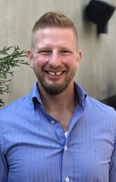 A man with short hair smiles at the camera
