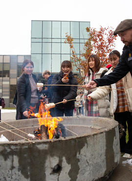 Students roasting marshmallows over a fire.