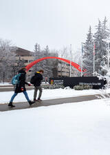 students walking past the main campus entrance during winter