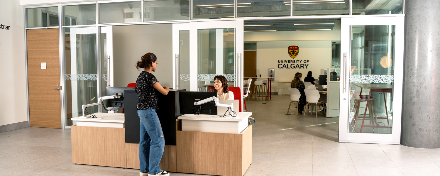 A female student stands at the reception desk of Enrolment Services